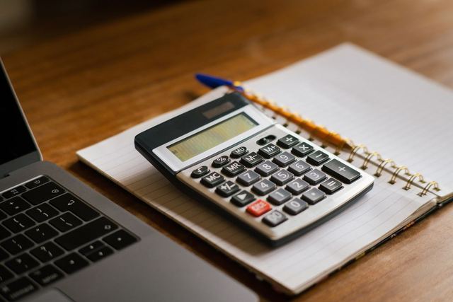 A calculator and notebook on a desk