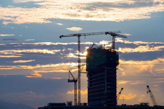 Cranes over a building under construction at sunset